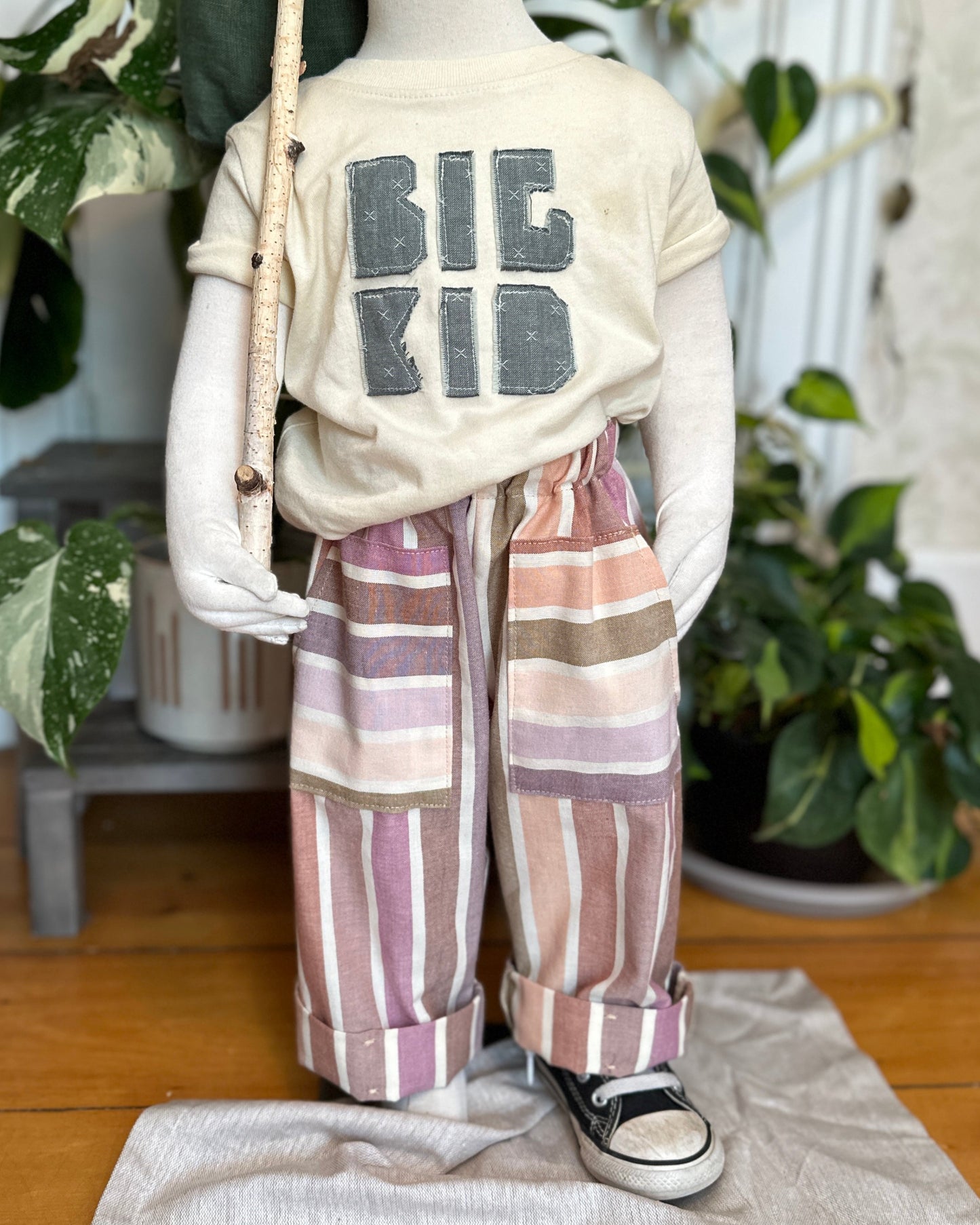 Mannequin wearing a 'BIG KID' t-shirt with striped pants in a home setting.