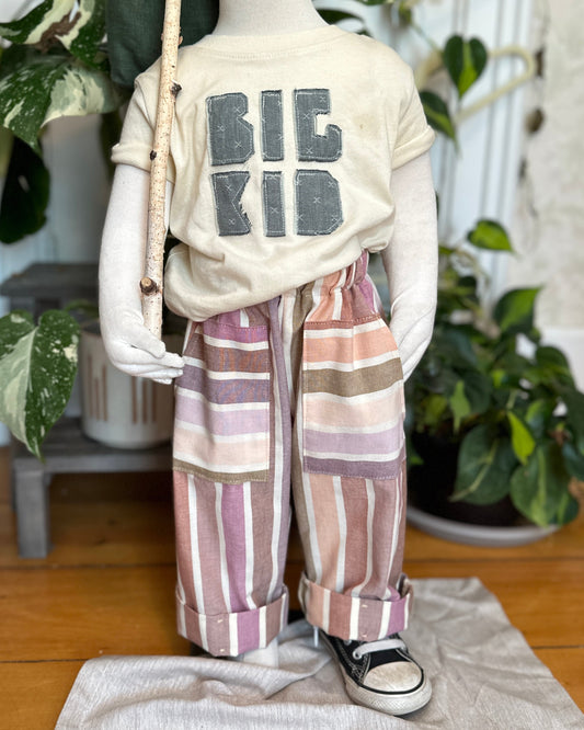 Mannequin wearing a 'BIG KID' t-shirt with striped pants in a home setting.