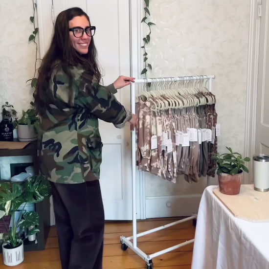 room to grow rompers hanging on clothing rack rolling into frame. one at a time each color romper is held in frame. Mauve Tie Dye, Grey Cactus, Willow Green, and then Mocha Shapes. 